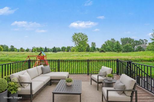 Expansive maintenance-free deck overlooking inviting back yard, creating the perfect setting for outdoor dining, entertaining, or simply relaxing while enjoying the peaceful views.(Virtually staged photo)