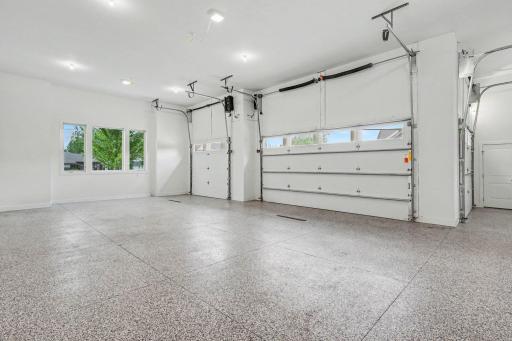 Expansive heated four-car garage with epoxy floors, oversized overhead doors, and exceptional space for vehicles, recreational equipment, and storage.