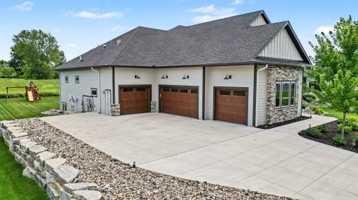 Oversized heated four-car garage with carriage-style doors, expansive driveway, and abundant space for vehicles, golf carts, storage, and hobbies.