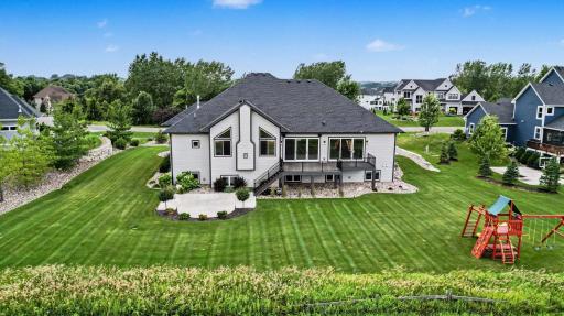 Beautiful backyard with lush landscaping, expansive lawn, and a spacious maintenance-free deck overlooking peaceful golf course views.