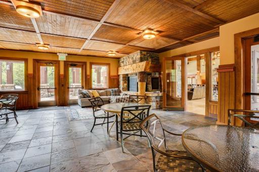 Warm and inviting clubhouse lounge featuring a floor-to-ceiling stone fireplace, rich wood finishes, and comfortable spaces for entertaining year-round.