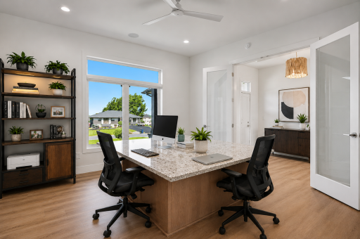 Main-level executive office with french doors, a custom built-in workspace for two people, oversized window, and an ideal layout for working from home. (Virtually staged photo)