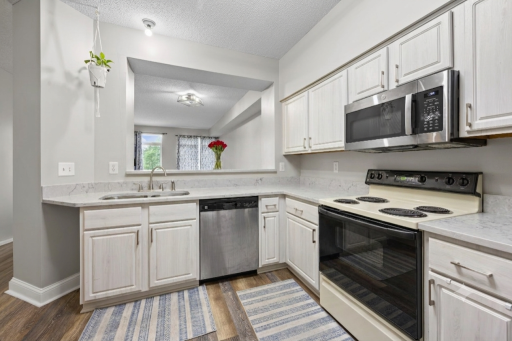 Updated kitchen with Quartz countertops, refinished cabinetry, and seamless pass-through and breakfast bar area between kitchen to living room. (Virtual staging has been used to help highlight this home's features)