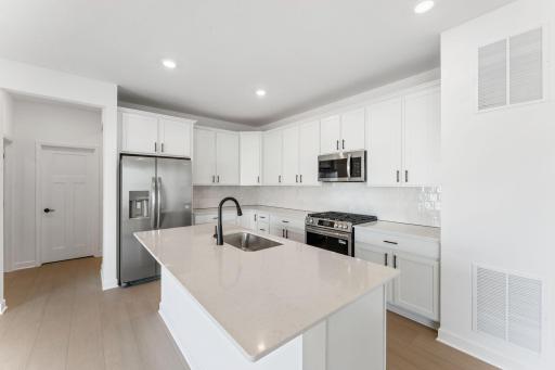 (Photo of a similar home, actual finishes may vary) The kitchen features an open and inviting layout with sleek Shaker-style cabinetry, all new stainless-steel appliances and a spacious center island.
