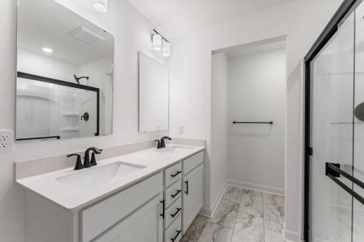 (Photo of a similar home, actual finishes may vary) The en-suite bathroom combines elevated style with functionality, featuring a glass-enclosed shower and floating vanity