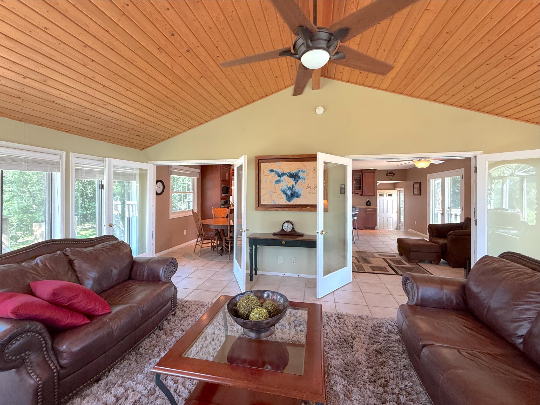 Designed for gathering, the spacious living room features vaulted knotty pine ceilings, expansive windows, and an open connection to the kitchen and dining room.
