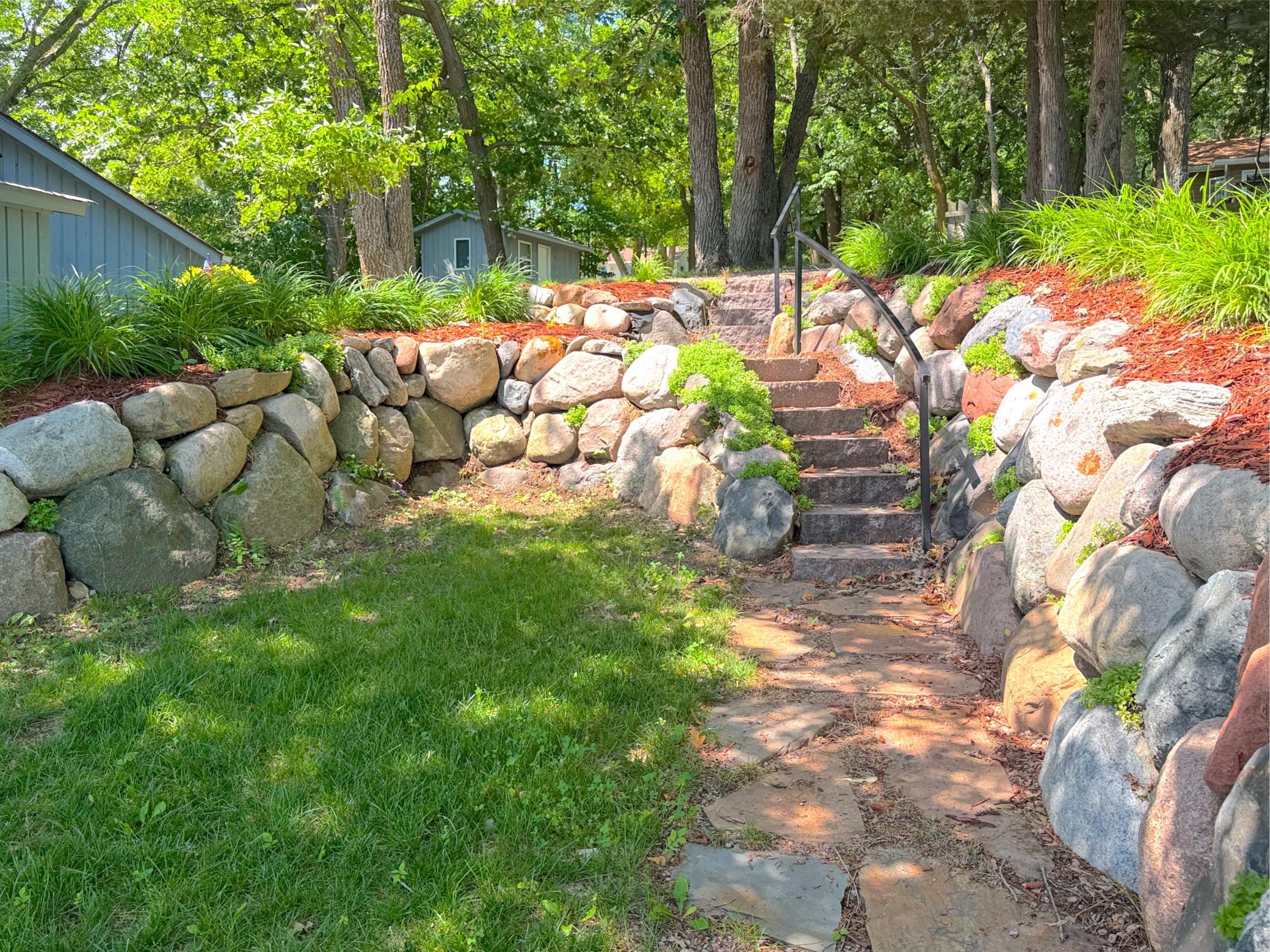 Quality craftsmanship is evident throughout the outdoor spaces, where custom railings, granite steps, and a flagstone walkway create a picturesque path to the Lake Sylvia shoreline.
