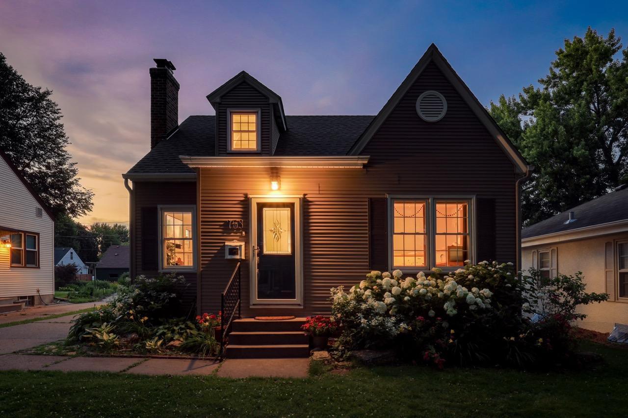 View of front of house with warm interior lights painting the landscaping