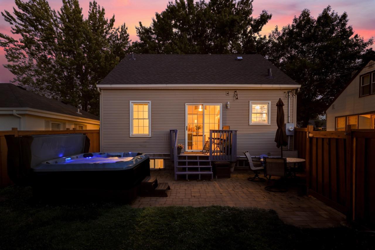 Twilight of the back hot tub, patio, deck and warm light emanating from inside the house.