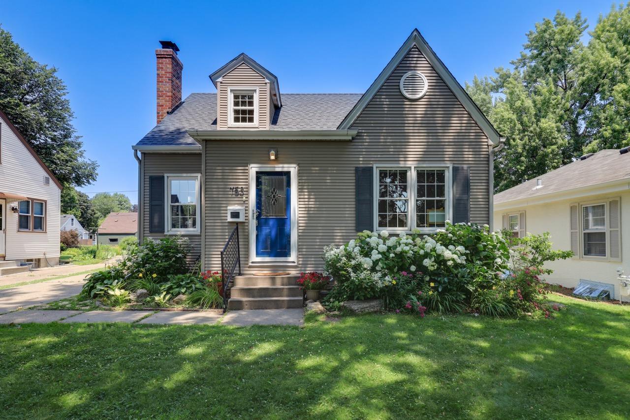 View of front of house with striking loyal blue door and full glass storm door and thoughtful landscaping decorates the front