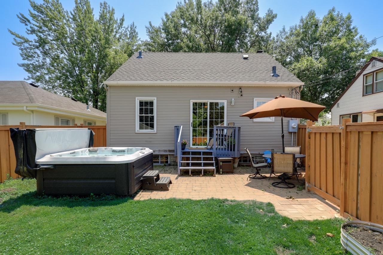 View of the back hot tub, patio, deck and sliding door and driveway gate