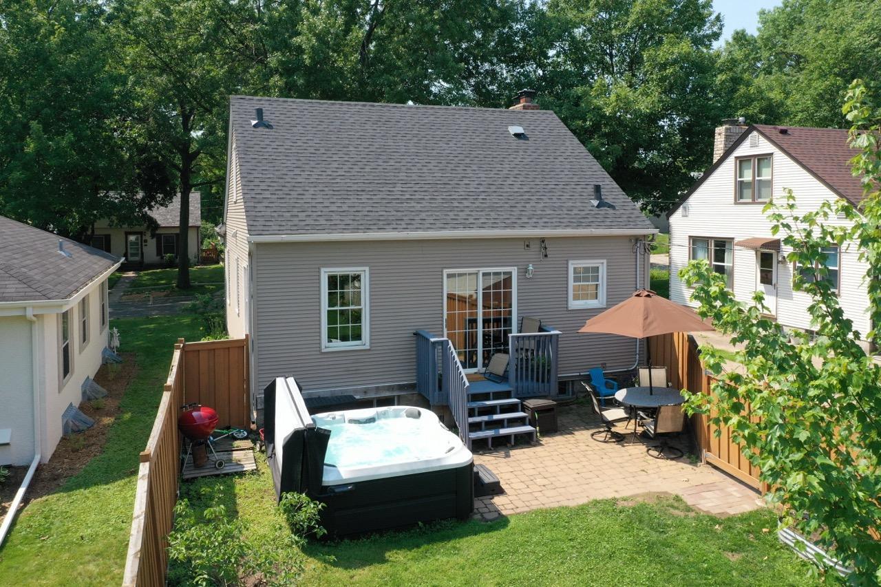 Elevated shot of the back of the house from the northeast showing the hot tub, patio, deck, and sliding door on back of house.