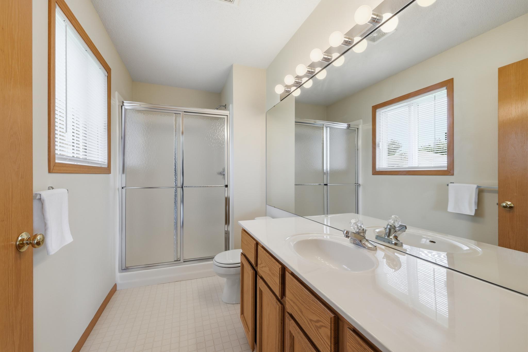 Private en-suite bath featuring a walk-in shower and expansive counter space, offering both comfort and everyday convenience.