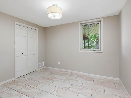LL Bedroom 5 offers natural light, tile flooring, and convenient closet storage.
