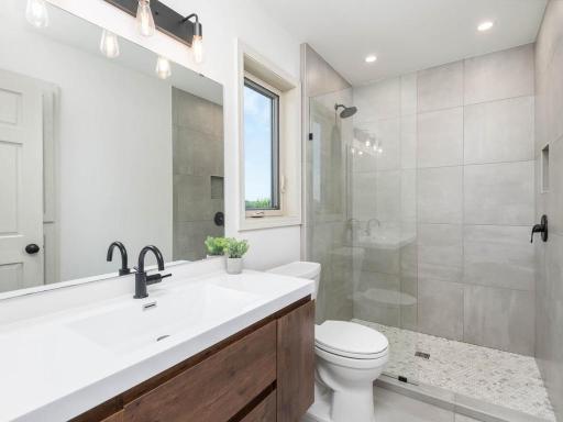 Private primary 3/4 bath features a tiled walk-in shower with glass enclosure and a spacious vanity.