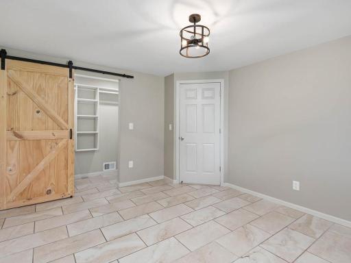 Lower-level bedroom 4 features a sliding barn door opening to a spacious walk-in closet.