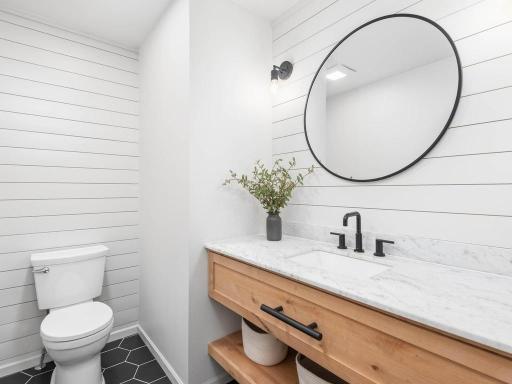 Remodeled main level 1/2 bath features shiplap walls, wood vanity, and black fixtures.