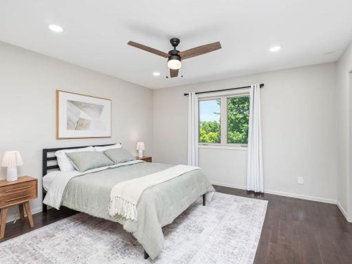 Upper-level primary bedroom features hardwood flooring, ceiling fan, natural light, walk-in closet, and private 3/4 bath.