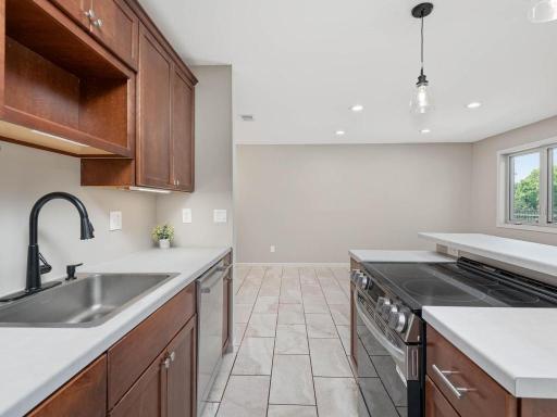 Lower-level kitchen provides functional prep and storage space with sink, range, cabinetry, and pendant lighting.