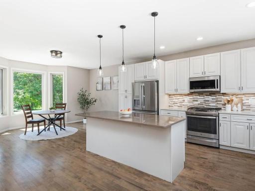 Kitchen offers generous workspace, pendant lighting, under-cabinet LEDs, and comfortable connection to the informal dining area.