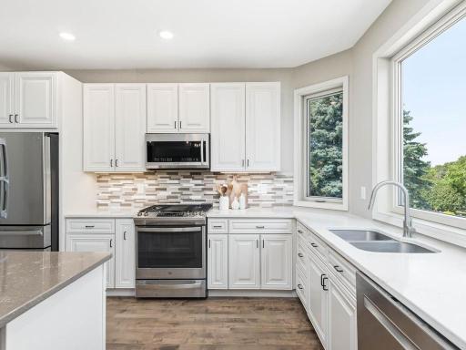 Kitchen features quartz countertops, SS appliances, tile backsplash, and windows overlooking the yard.
