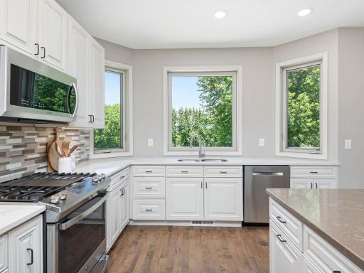 Multiple kitchen windows bring in natural light above the expansive quartz countertops and white cabinetry.