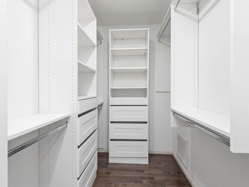 Finished primary walk-in closet includes built-in organizers, shelving, drawers, and hanging space.