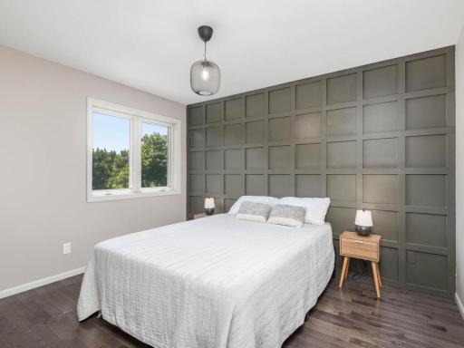 Upper-level bedroom 2 features hardwood flooring, natural light, and a distinctive paneled accent wall.