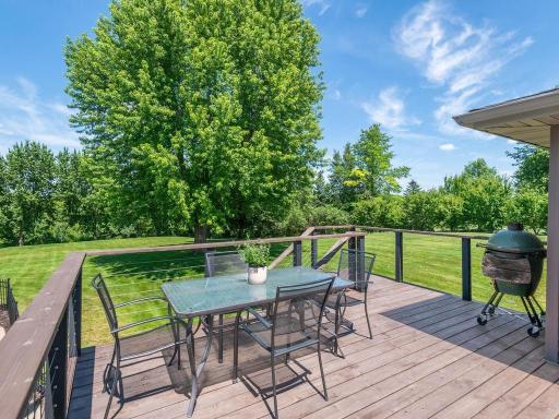 Cedar deck features a single-level design, metal railings, and generous space for outdoor dining, grilling, and relaxing while overlooking the landscaped acreage.
