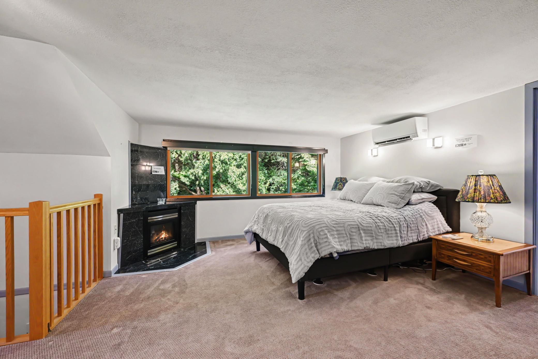 Primary Bedroom w/ gas fireplace and windows facing wooded backyard