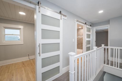 Upper level hallway looking into bedroom, currently used as laundry room, and full bathroom down the hall.
