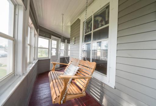 Enclosed porch with porch swing on front of house