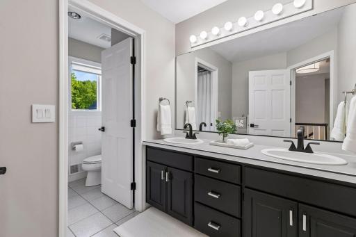 A full upper-level bathroom features a separate vanity area, allowing multiple people to use the space at the same time.