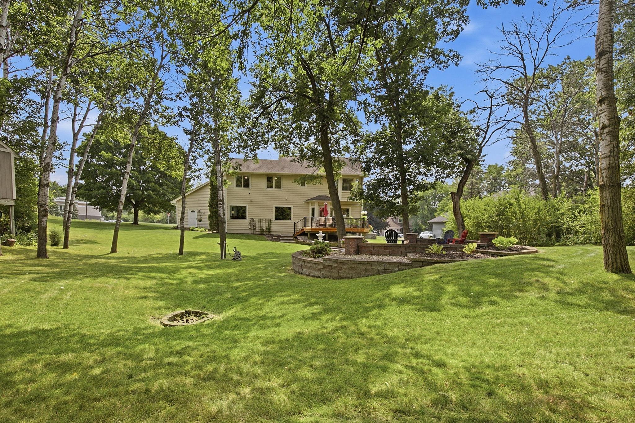 Beautifully maintained backyard offers the perfect balance of open lawn and outdoor living spaces.
