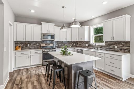 Gorgeous kitchen with an abundance of white cabinetry, quartz counters and tile backsplash.