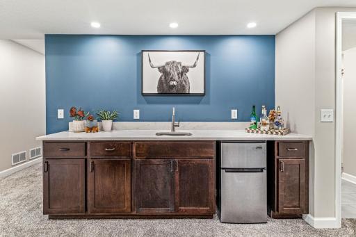 Walk up wet bar with quartz counter, sink and beverage frig.