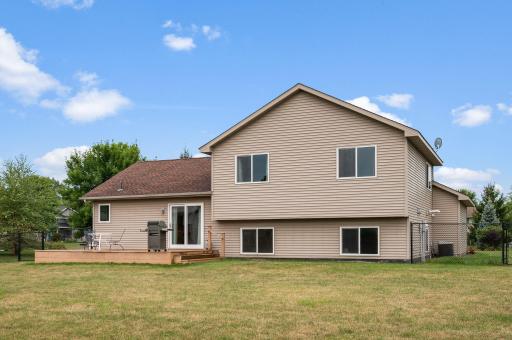 Rear exterior view showing the two-story split-entry layout, walkout deck, and expansive back lawn