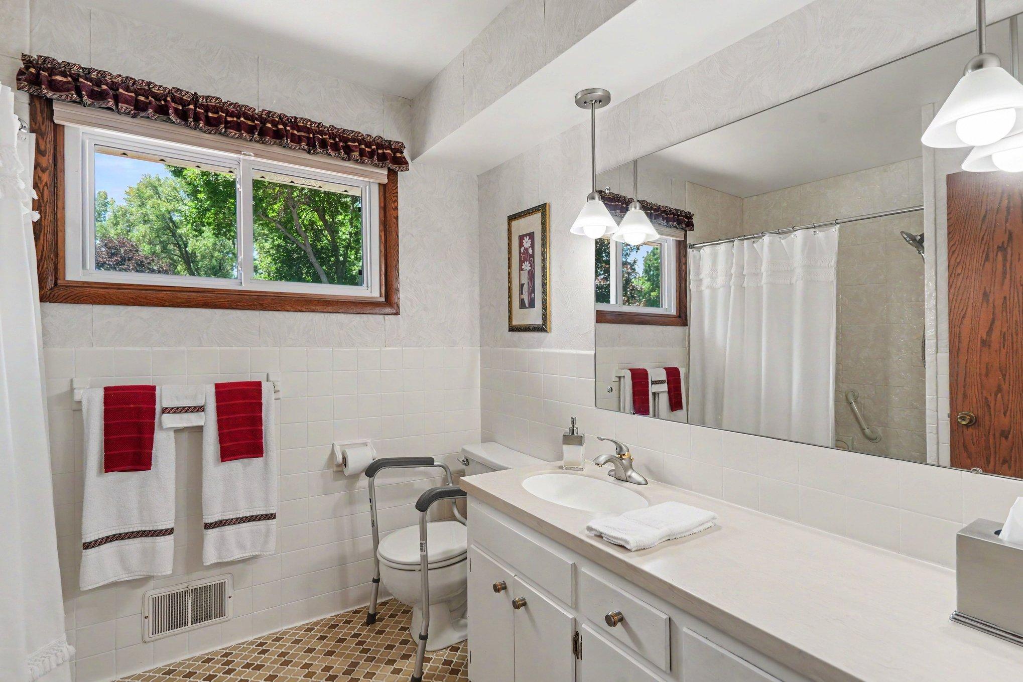 Upper level full bath with Corian counter vanity, tiled floors and linen closet behind the door.