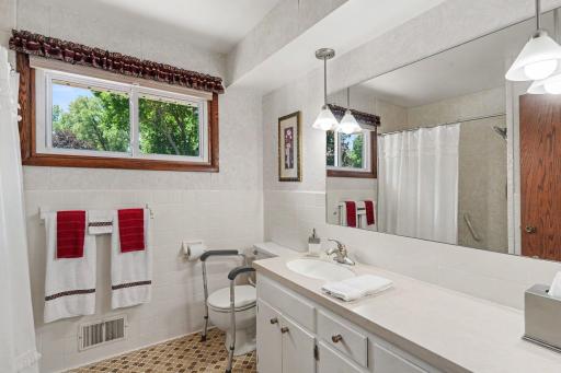 Upper level full bath with Corian counter vanity, tiled floors and linen closet behind the door.