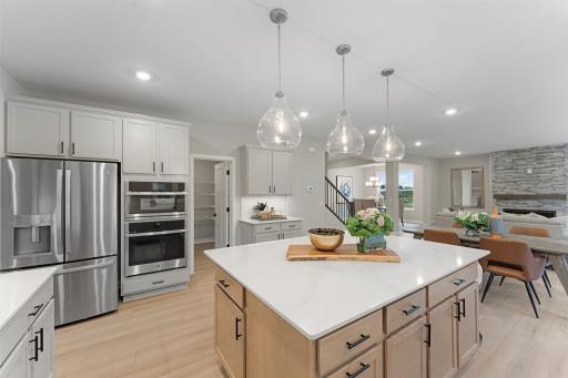 (Photo of a similar home, actual finishes may vary) A spacious center island stands at the heart of this optional gourmet kitchen with included nickel pendant light fixtures