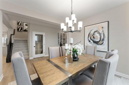 (Photo of a similar home, actual finishes may vary) The dining room is partially sequestered from the rest of the open living spaces