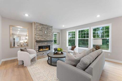 (Photo of a similar home, actual finishes may vary) Tall windows bring ample natural light into the Great Room, while a fireplace adds a warm glow on cold nights