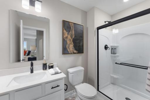 (Photo of a similar home, actual finishes may vary) A private bathroom offers a shower with built-in shelves and a quartz-topped vanity with a MoenÂ® chrome-finish faucet