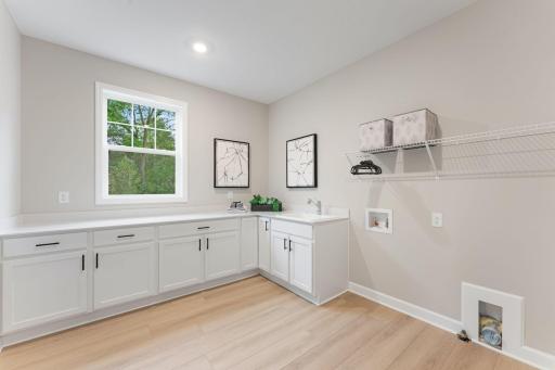 (Photo of a similar home, actual finishes may vary) Situated in a discreet corner on the first floor, this large laundry room provides ample space to complete daily household chores and other organizational tasks.