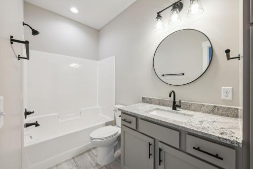 Main level full bathroom with tile flooring and granite tops - *Photo of previous spec - colors may vary on current spec home*