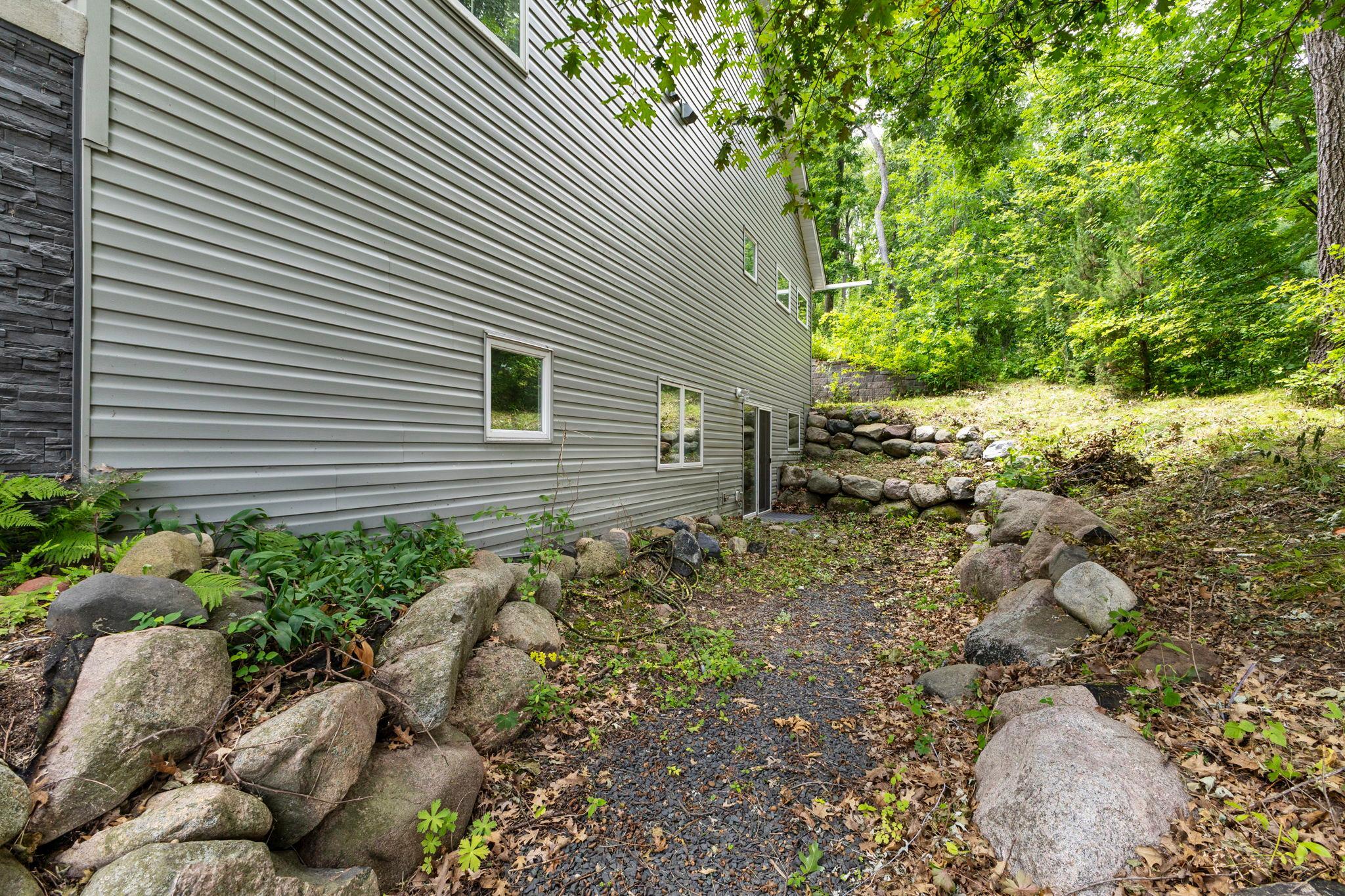 Lower-level walkout leads you to this private & cozy gravel area on the side of the house.