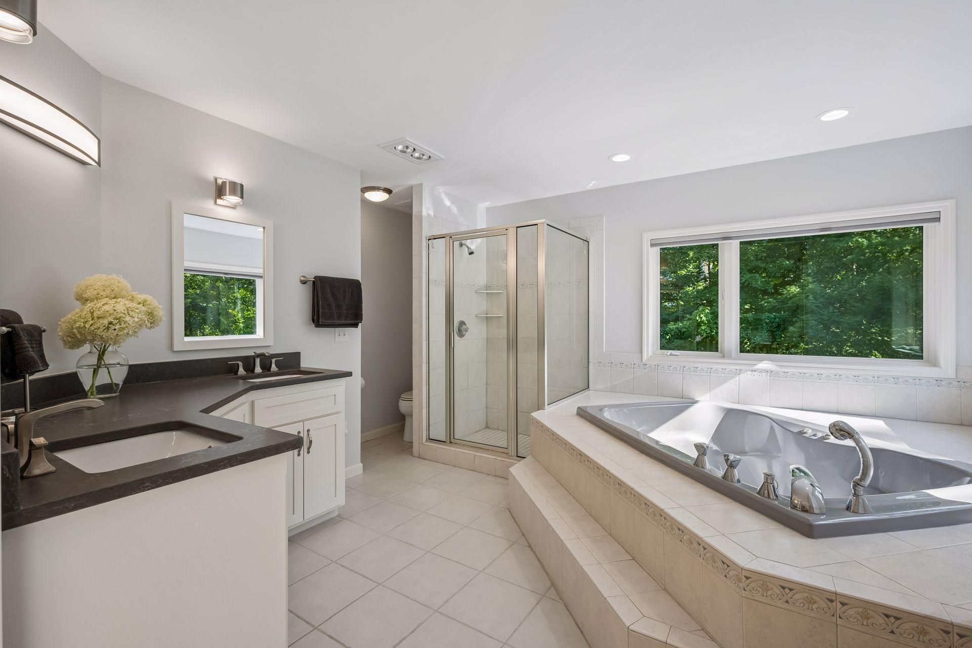 Primary bath features dual sink vanity, jetted Whirlpool tub, large separate glass shower, and electric heated floors