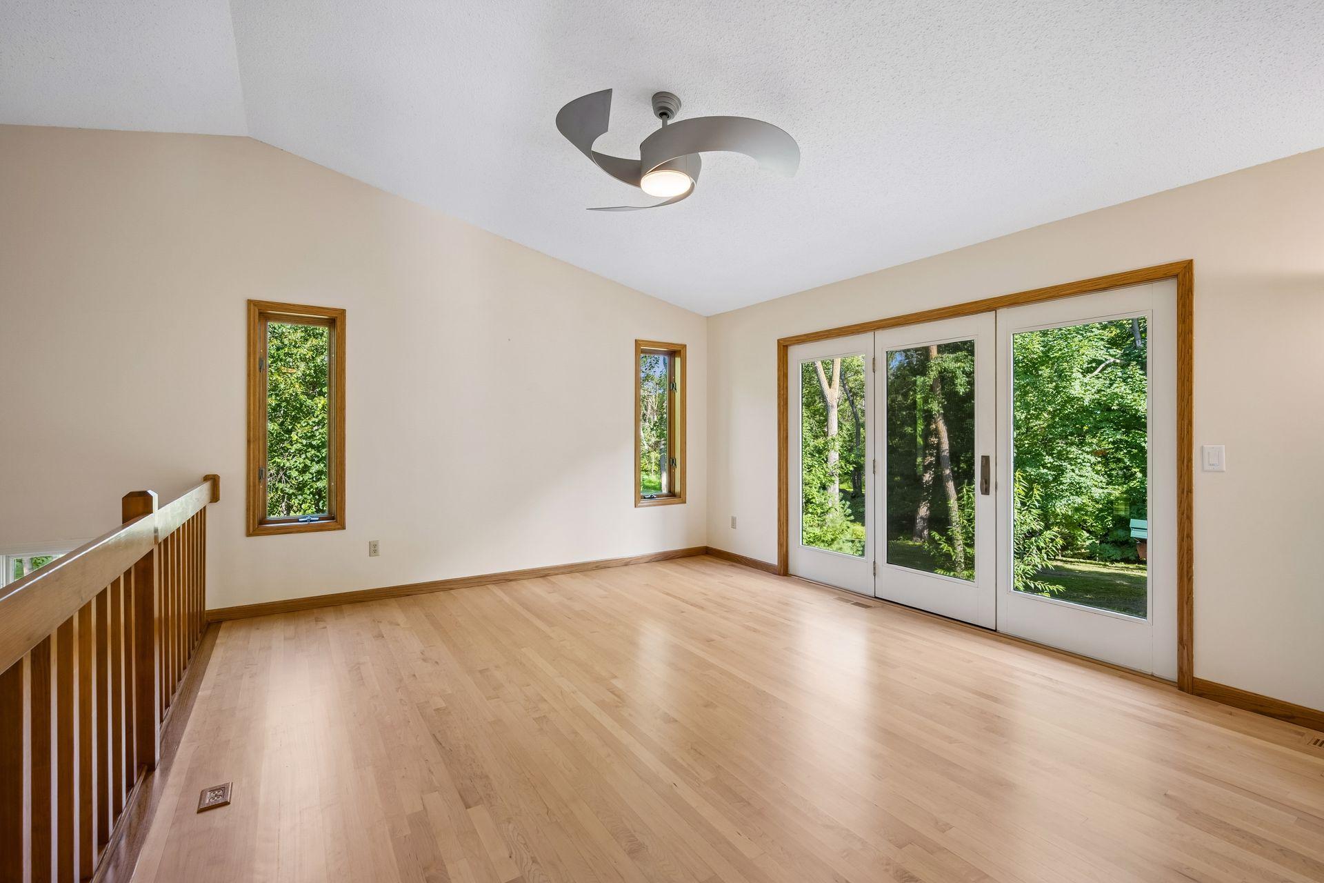 Upper level living room features freshly refinished maple hardwood floors, a vaulted ceiling, and outdoor views