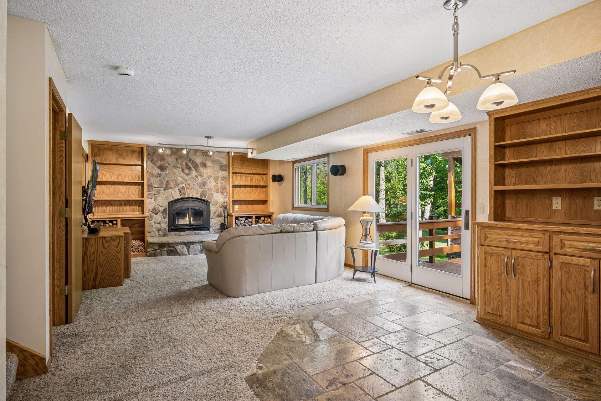 Lower level family room is the perfect gathering and entertaining area, with a cozy wood-burning fireplace insert, access to the rear deck, and custom built-ins