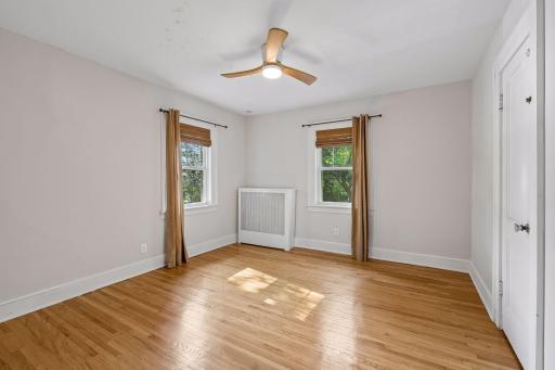 Second upper-level bedroom with hardwood floors, updated ceiling fan and abundant natural light.